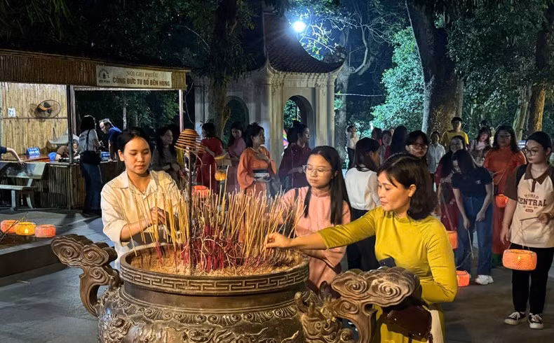 Tourists offering incense in a solemn, quiet atmosphere at Hung Temple at night.
