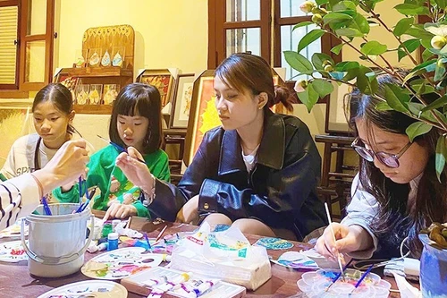 Young people try their hand at creative work on Bodhi leaves.