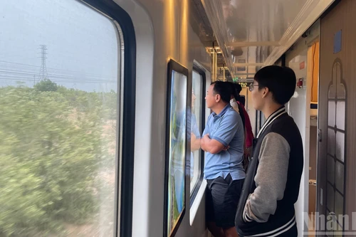 Passengers enjoy the scenery through the carriage windows.