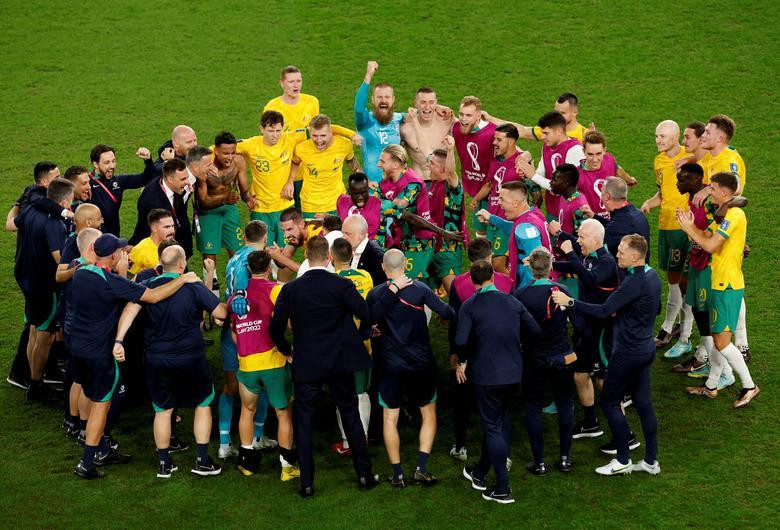 Australia coach Graham Arnold celebrates with his players and staff after qualifying for the knockout stages. REUTERS/Albert Gea