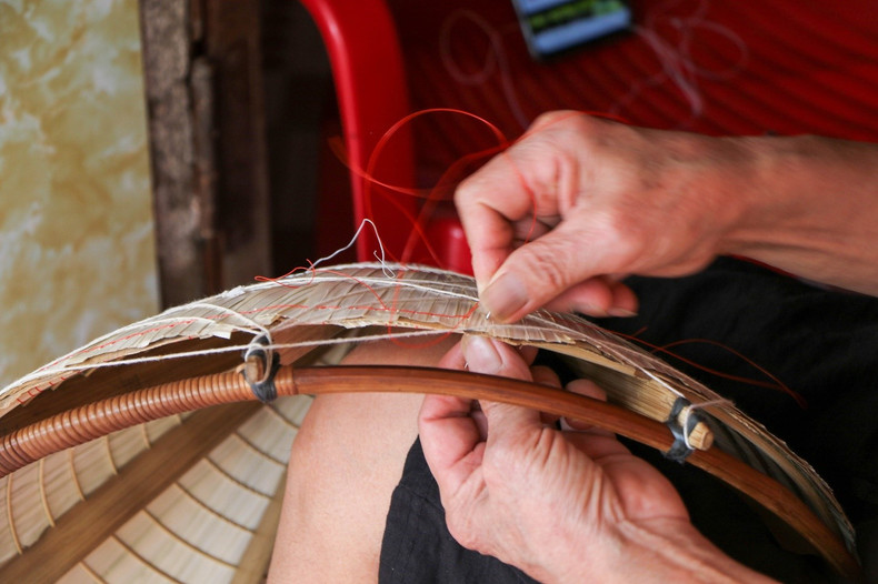 The meticulous hands of the craftsman carry out each stage to form the conical hat. The meticulous hands of the craftsman carry out each stage to form the conical hat.