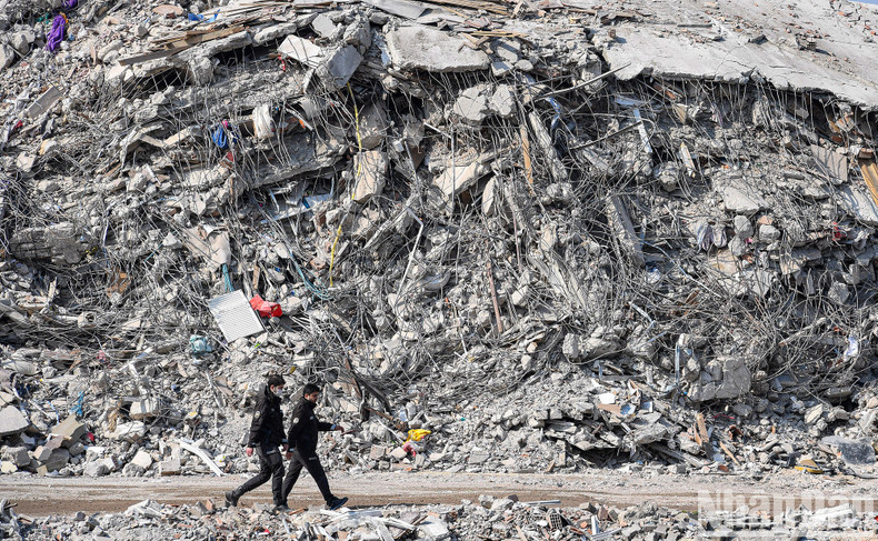 Two police officers walk past the ruins of fully destroyed buildings. Two police officers walk past the ruins of fully destroyed buildings.