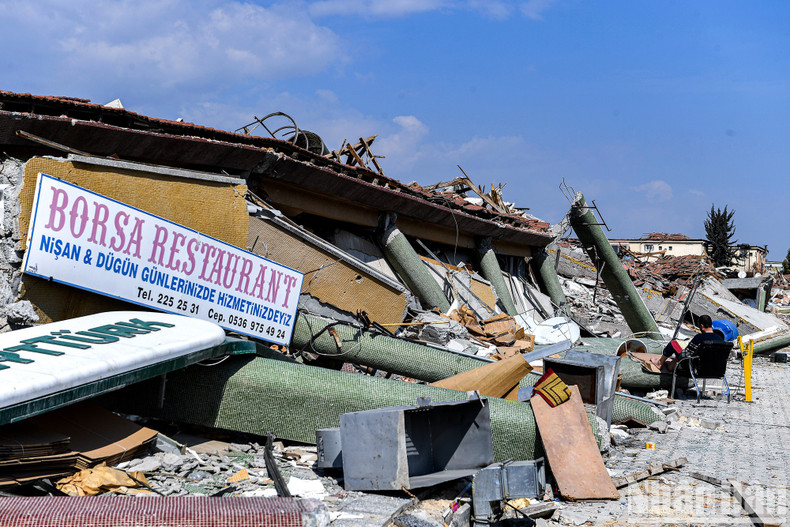 A man read books next to the ruins of a collapsed building. A man read books next to the ruins of a collapsed building.