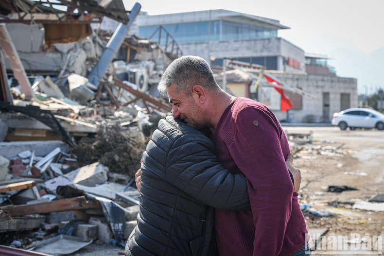 Two acquaintances hug after learning that the other is safe near a collapsed building in Hatay. Two acquaintances hug after learning that the other is safe near a collapsed building in Hatay.