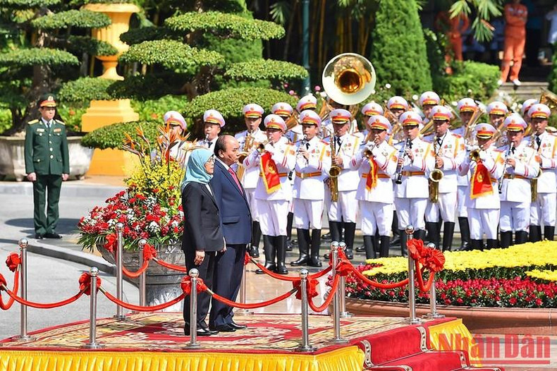 President Nguyen Xuan Phuc and his Singaporean counterpart listen to the playing of the two countries’ national anthems.