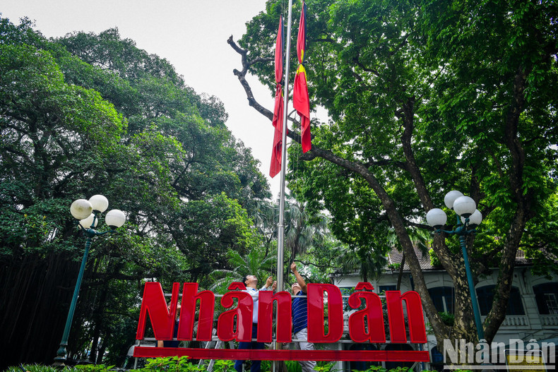 Nhan Dan staff solemnly lower the flags to half-mast.