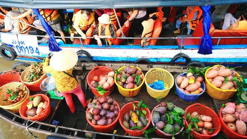 Visitors experience buying fruits at the Cai Rang floating market.
