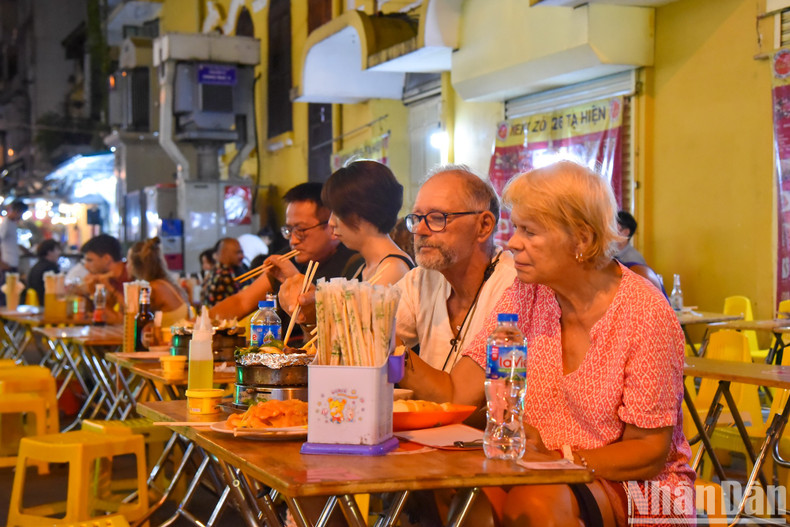 Foreign tourists enjoy local delicacies at Ta Hien Street. Foreign tourists enjoy local delicacies at Ta Hien Street.