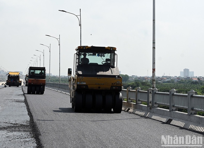 Workers are paving the bridge’s surface with concrete asphalt.