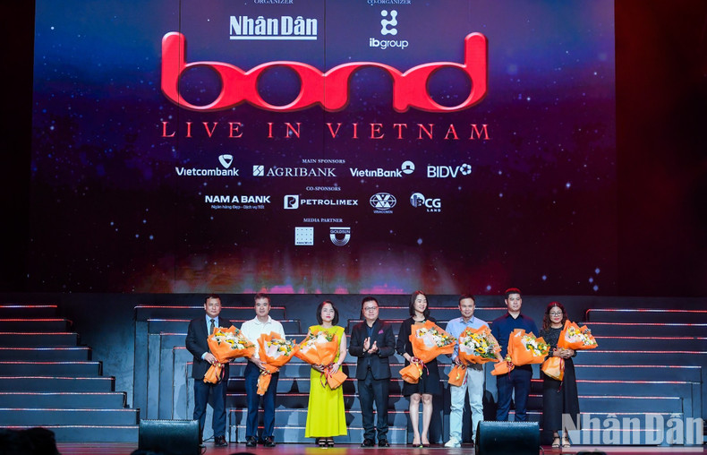 Nhan Dan’s Editor-in-chief Le Quoc Minh presents flowers the concert’s sponsors ahead of the Bond performance. Nhan Dan’s Editor-in-chief Le Quoc Minh presents flowers the concert’s sponsors ahead of the Bond performance.