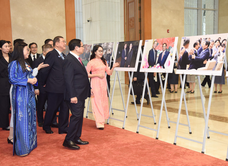 Vietnamese PM Pham Minh Chinh, Japanese PM Ishiba Shigeru and their spouses look at photos on bilateral cooperation.