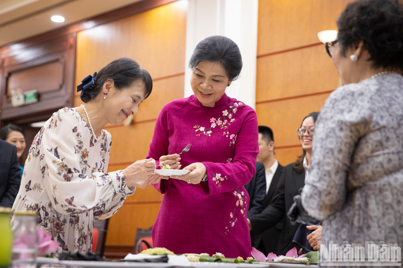 The two ladies taste the banh com they made.