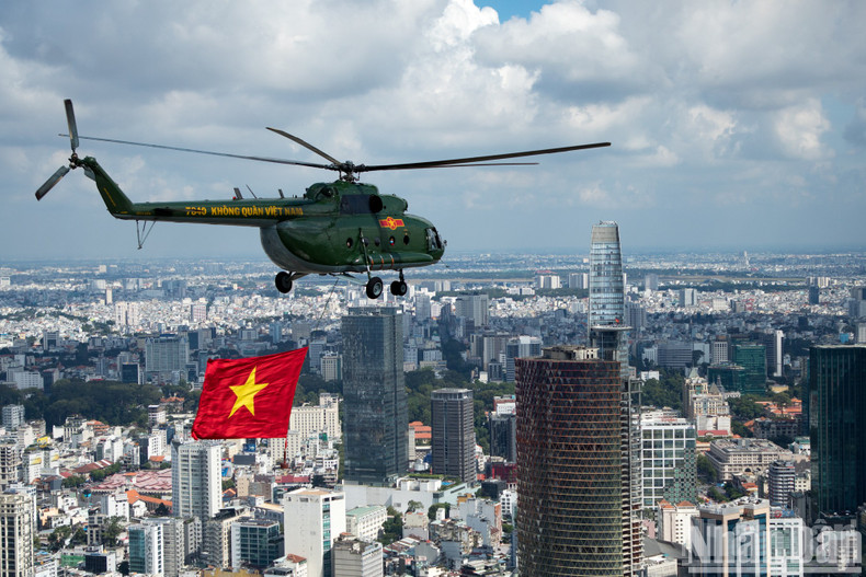 A helicopter pulling the national flag flies past the Bitexco building (District 1).
