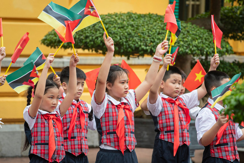 Vietnamese children wave flags to welcome Mozambican President Filipe Jacinto Nyusi.