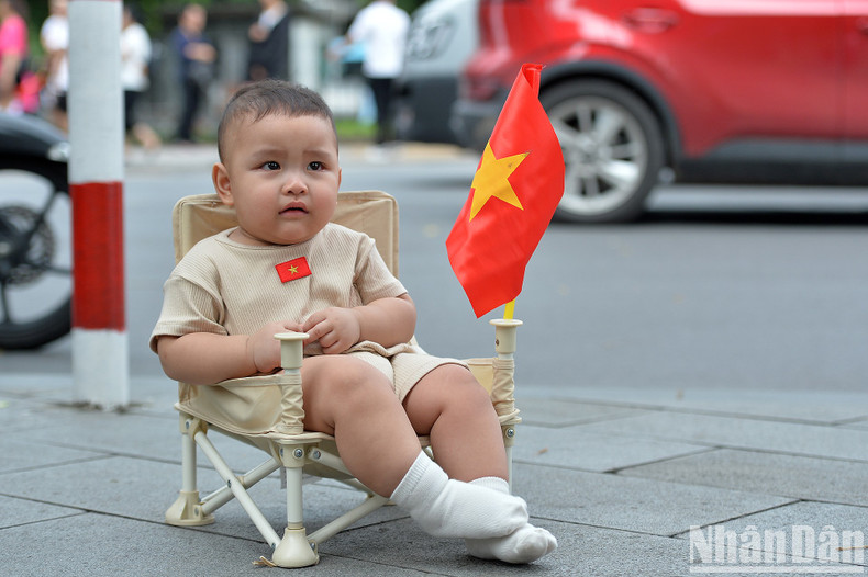 A baby is walked along the street with a national flag badge on his clothes. A baby is walked along the street with a national flag badge on his clothes.