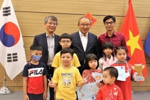 Ambassador Nguyen Vu Tung (left, behind) and coach Park Hang-seo (centre, behind) in a photo with Vietnamese children (Photo: VNA)