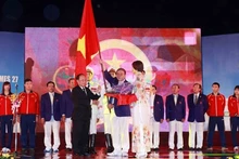 Minister Hoang Tuan Anh (left) presents the national flag to Lam Quang Thanh, head of the Vietnam sports delegation 