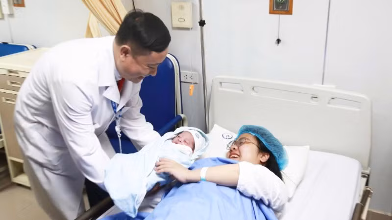 Associate Professor Dr Vu Van Du, Deputy Director of the National Hospital of Obstetrics and Gynaecology, congratulates the mother.