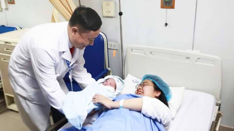 Associate Professor Dr Vu Van Du, Deputy Director of the National Hospital of Obstetrics and Gynaecology, congratulates the mother.