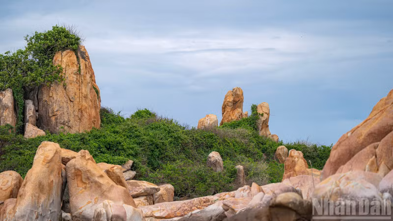 Surrounding the historic tower are striking rock formations, seemingly scattered at random, forming a rugged barrier against the open sea.