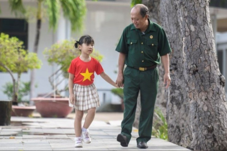 Master Sergeant Nguyen Chi Tuong with the child of a Vinamilk employee at the Long Dat Centre for the Care of Wounded Soldiers and Contributors to the Nation. (Photo: THANH BINH)