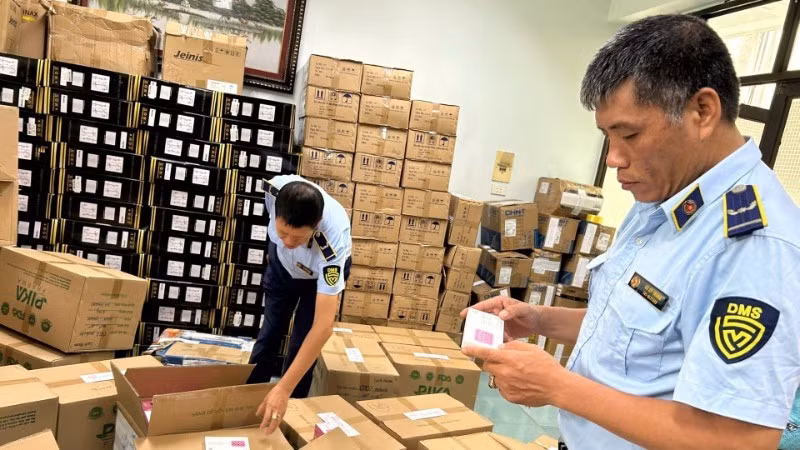 Ha Noi market surveillance officers inspect a business establishment suspected of violations. (Photo: Luu Quyen)