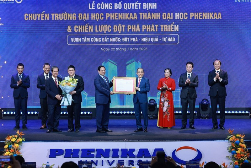 Prime Minister Pham Minh Chinh (fifth, right) hands over the Government’s decision allowing Phenikaa University to expand from a multi-disciplinary institution into a university with multiple member schools across various fields. (Photo: VNA) 