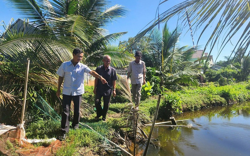 Nam Dau (middle) and local officials visit the site to resolve the conflict over land between two households.