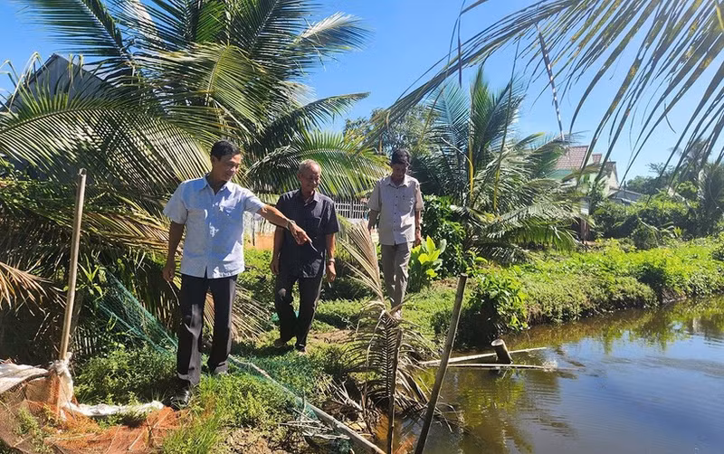 Nam Dau (middle) and local officials visit the site to resolve the conflict over land between two households.