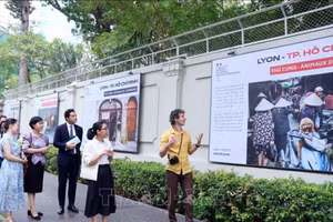 Adrien Jean (right) introduces his photos at the exhibition (Photo: VNA)