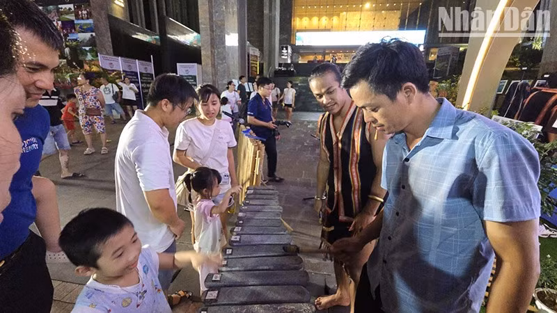 Visitors experience a lithophone under the guidance of an ethnic minority artist from Gia Lai Province. (Photo: PHUC THANG)