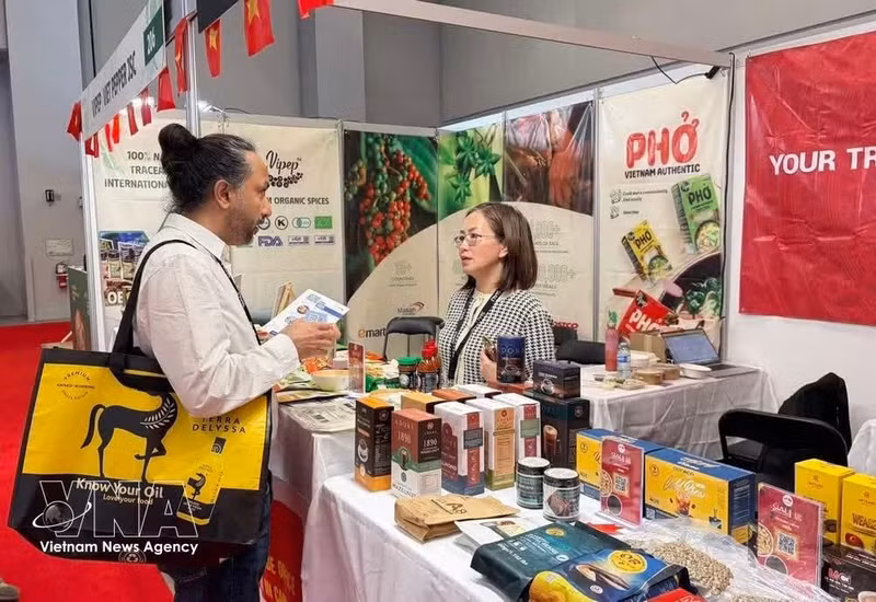 A Canadian customer speaks with a representative of the Viet Nam Trade Office while visiting the pavilion. (Photo: VNA)