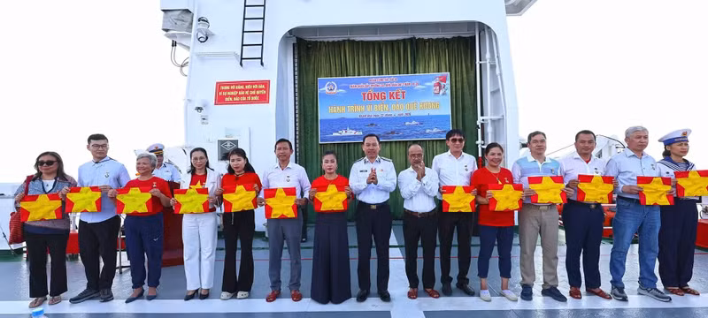 Rear Admiral Ho Thanh Hoan presents overseas Vietnamese delegates with national flags stamped by the islands.