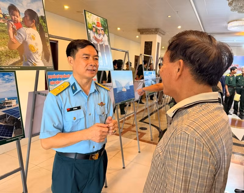 Journalist Vu Hai Ha (left) shares the stories behind his photographs. (Photo: HA NAM)