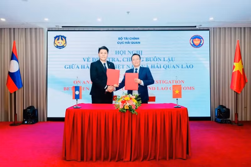 Leaders of the Anti-Smuggling Investigation Departments of Viet Nam and Laos exchange the signed meeting minutes.