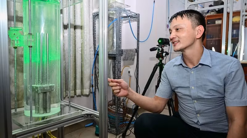 Researcher Tran Thanh Tram (Nuclear Training Centre) demonstrates natural convection in a fuel rod assembly. (Photo: BAO LONG)