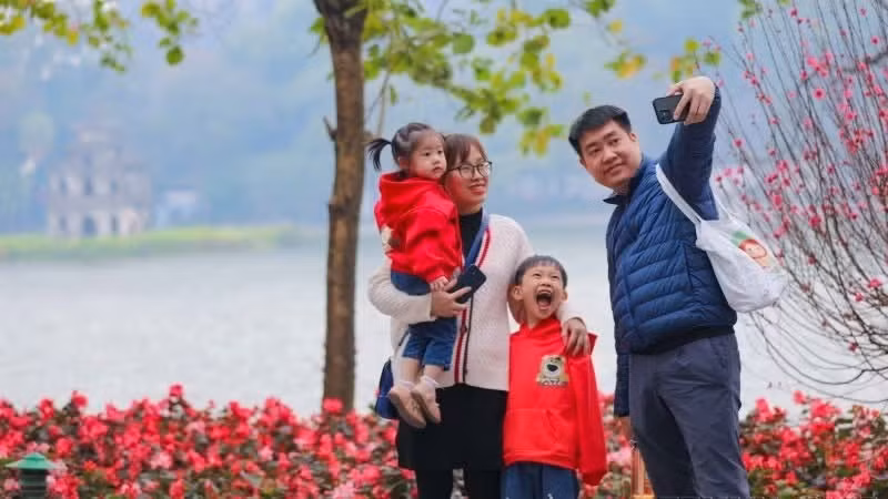 A family captures a springtime moment together by Hoan Kiem Lake. (Photo: Thanh Tung/VNA)