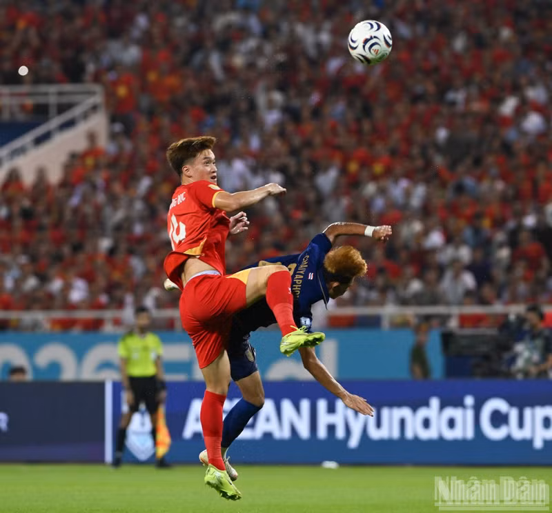 Hoang Duc challenges a Thai player for an aerial ball.