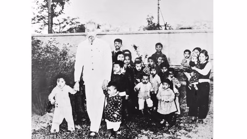 President Ho Chi Minh poses with children for a commemorative photograph during his visit to Nhan Dan Newspaper in 1957.