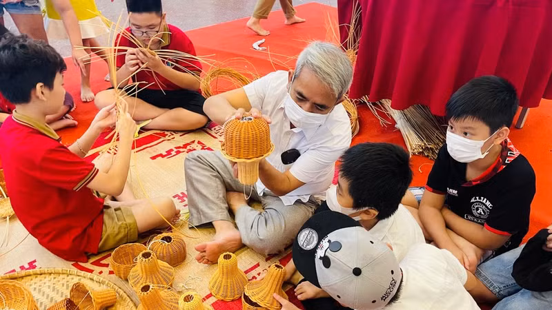 Children make traditional handicrafts with artisans. (Photo: Organising Committee)
