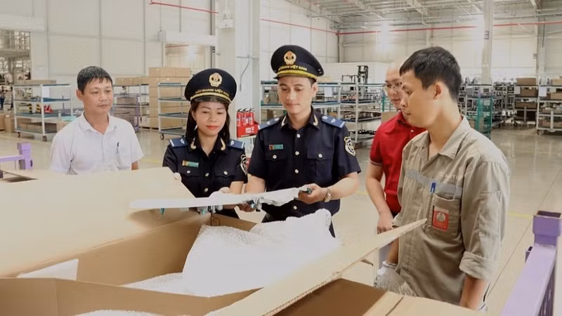 Customs officials check the list of duty-free goods. (Photo: BUI NU)