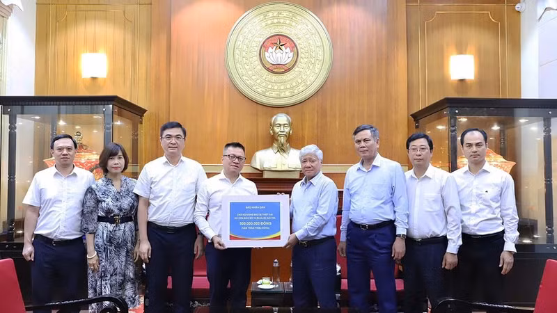 Do Van Chien (4th from right) receives the donation from the leaders, cadres, and employees of Nhan Dan Newspaper. (Photo: NDO)
