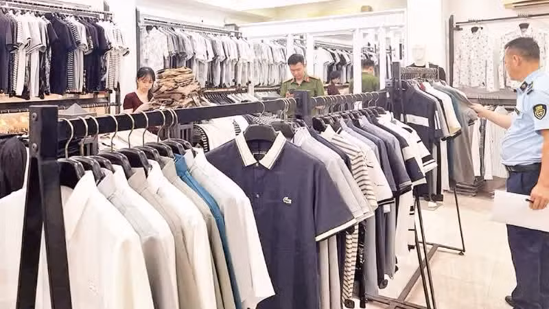Authorities inspect a fashion store in Tay Tuu Ward, Ha Noi, for trading products counterfeiting international brands. (Photo: TUAN NGOC)