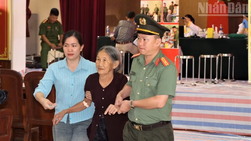 Police officers and officials from Giai Lac Commune assist relatives of martyrs at a DNA sample collection point. (Photo: NDO)