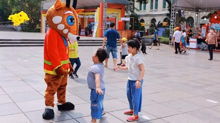 Children interacting with Saola, the mascot of SEA Games 31, at Hanoi Tourism Gift Festival 2022. (Photo: NDO/Giang Nam)