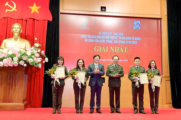Deputy Minister of Public Security Nguyen Van Thanh and Permanent Vice Chairman of the Vietnam Journalists' Association Ho Quang Loi present the first prize to the winning authors.