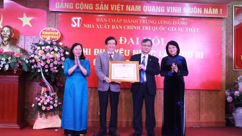 Vice President Dang Thi Ngoc Thinh presents the PM's certificates of merit to the Truth National Political Publishing House. 