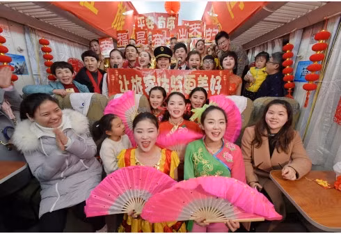 Attendants pose for a photo with passengers on the train Z68 from Nanchang, east China's Jiangxi Province to Beijing, capital of China, Feb. 13, 2018. A Spring Festival gala was held by the attendants on the train to bring happiness to the passengers. (Photo:Xinhua)