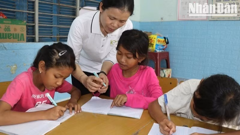 Teacher Vo Nguyen Thuc Van gently guides a pupil’s hand as they carefully practise each letter.