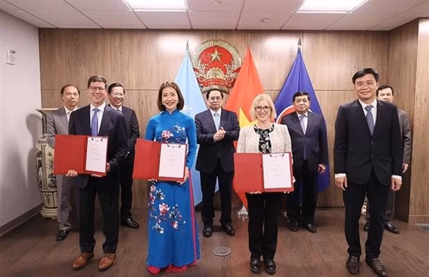 PM Chinh witnesses the exchange of investment agreements between firms of the two countries. (Photo:VNA)